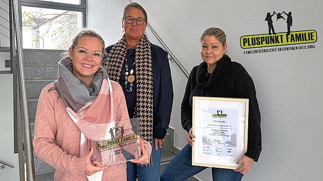 Drei Mitarbeiter der Stadtwerke Schwerte im Hausflur des Verwaltungsgebäudes präsentieren Award und Urkunde mit dem Schriftzug "Pluspunkt Familie. Familienfreundliches Unternehmen Kreis Unna."