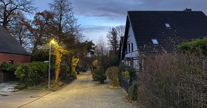 Eine ruhige Wohnstraße in Schwert bei Nacht mit eingeschalteter Straßenbeleuchtung gegenüber eines alten Fachwerkhauses