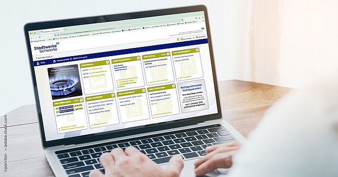 Es ist ein Laptop zu sehen vor dem ein Mensch sitzt. Auf dem Bildschirm sieht man symbolhaft eine Seite der Website der Stadtwerke Schwerte