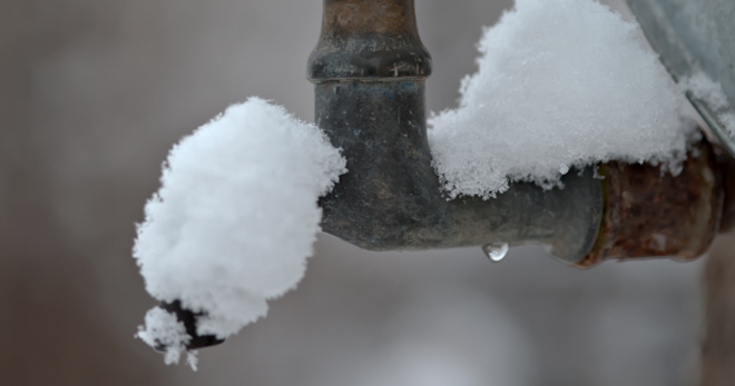 Eine alte Rohrleitung, die an zwei Stellen mit Schnee bedeckt ist als Symbol für Frostschäden