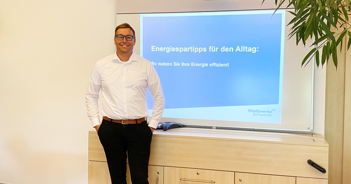 Ein Mitarbeiter der Stadtwerke Schwerte vor einer Projektionsleinswand mit dem Titel "Energiespartipps für den Alltag"