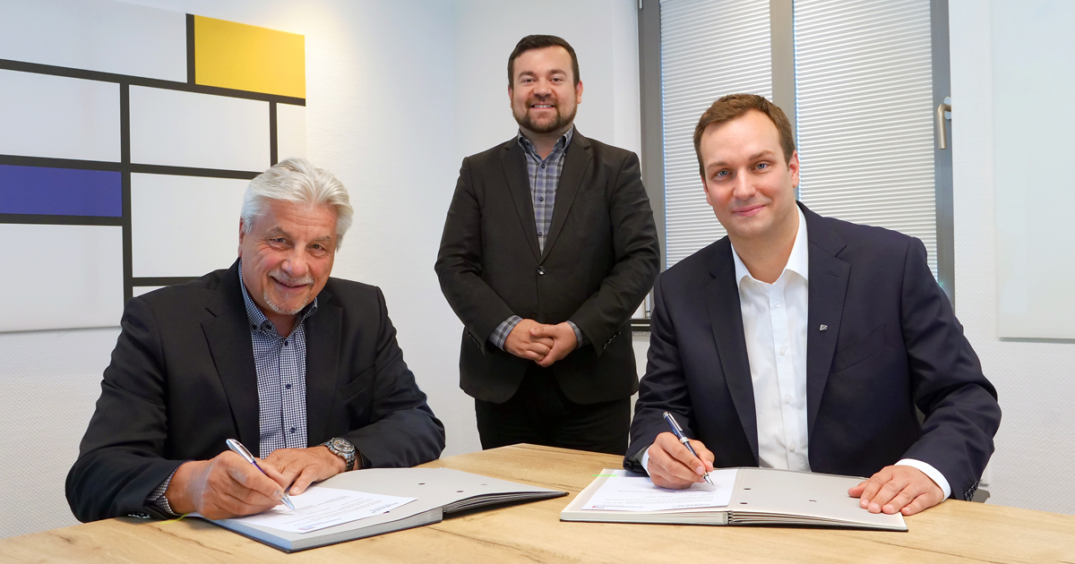Egon Schrezenmaier und Sebastian Kirchmann unterzeichnen jeweils ein Dokument, im Hintergrund der Schwerter Bürgermeister , Dimitrios Axourgos