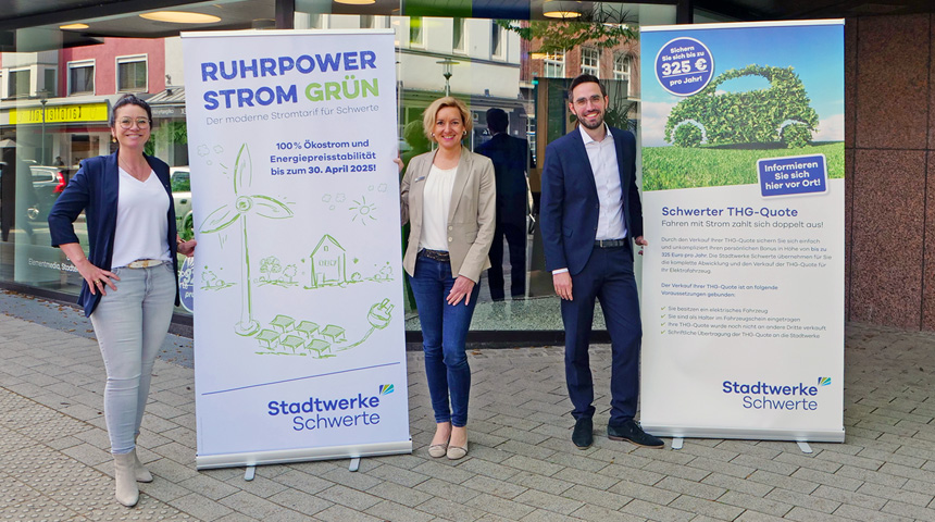 Drei Personen vor zwei Roll-Ups mit Werbeinformationen zu den Themen "Ruhrpower Strom Grün" und "Schwerter THG-Quote"