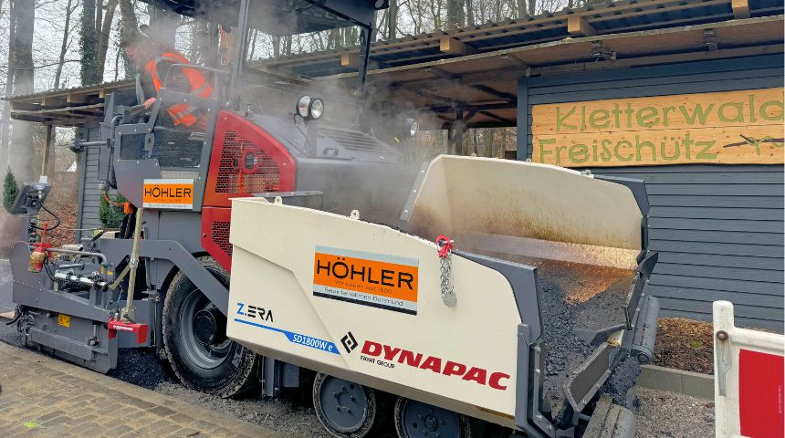 Dynapac Straßenfertiger mit Höhler-Branding bei Asphaltarbeiten vor dem Eingang des Kletterwald Freischütz