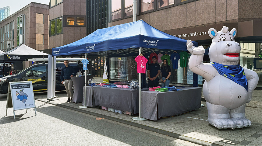 Der Stand der Stadtwerk Schwerte. Davor steht ein XXL-Nilpferd und viele bunte T-Shirts hängen an dem Verkaufszelt, das ein blaues Dach hat.